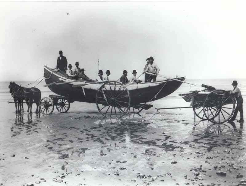 A U.S. Life-Saving Service horse hauls a heavy surfboat toward the ocean.