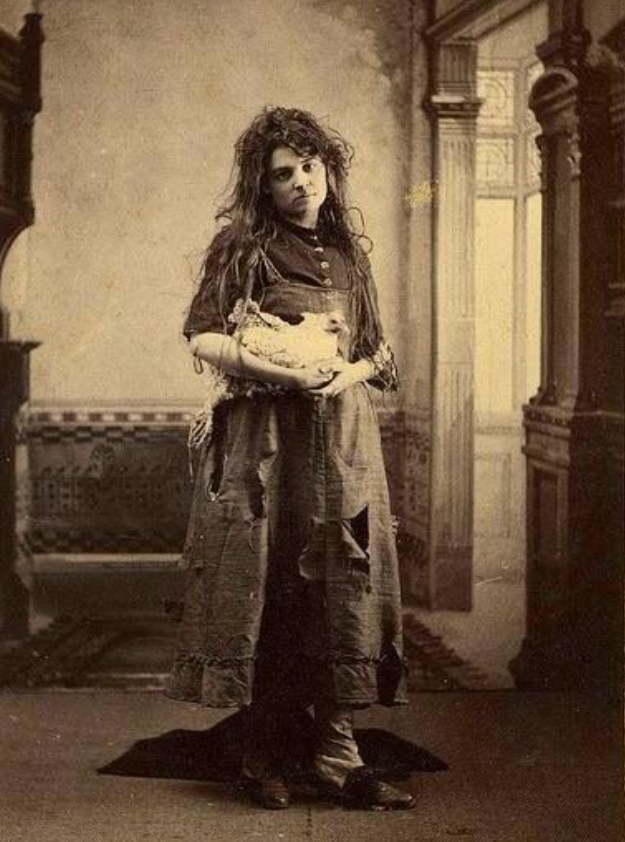A vintage photo showing a woman in modest clothing holding a chicken.